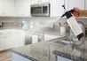 Person spraying a high-performance Kitchen and Bath Mister over a kitchen surface for cleaning.